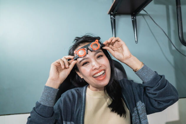 女人一位美丽的女士拿着正在眼科诊所房间里使用的测量眼镜摆姿势验光医学设备