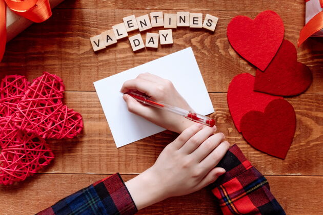 信息女孩的手写情书情人节手工制作的带有红色心形图案的贺卡2月14日是庆祝的日子从上面看女人爱礼物
