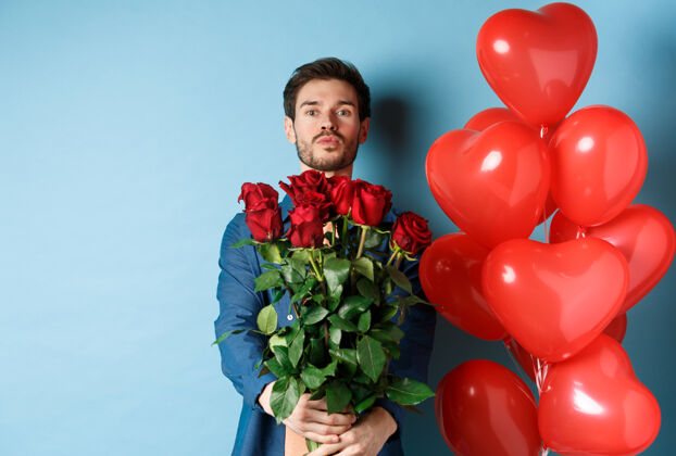感情浪漫的男朋友在爱中坦白 送上一束玫瑰 撅起嘴唇亲吻 蓝色背景上站着心形气球惊喜玫瑰关系