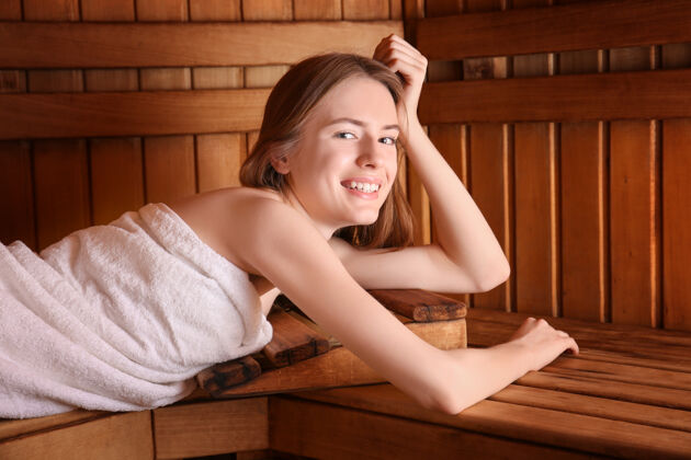 纯粹躺在桑拿房木凳上的年轻女子健康水疗热