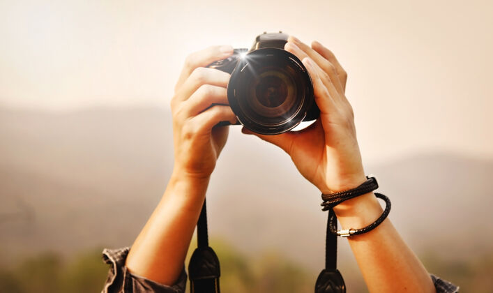 拍摄拍摄风景 特写年轻的亚洲男摄影师在拿着相机显示山全景