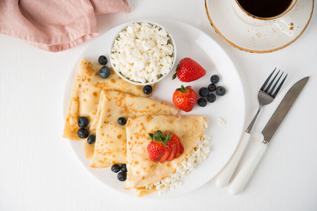 早晨传统的俄罗斯薄煎饼与白干酪和浆果在一个盘子里 俯视图早餐美食法国