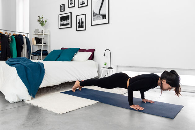 体位法在现代卧室的瑜伽训练课程中练习chaturanga姿势的健身女士卧室思想力量