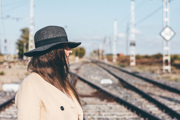 幻想在废弃的铁轨上穿着米色风衣戴着帽子的神秘女人秘密问题隐藏