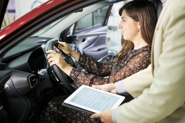服务汽车沙龙经理拿着平板电脑站在那里 向女顾客建议为她的新车投保运输汽车坐席
