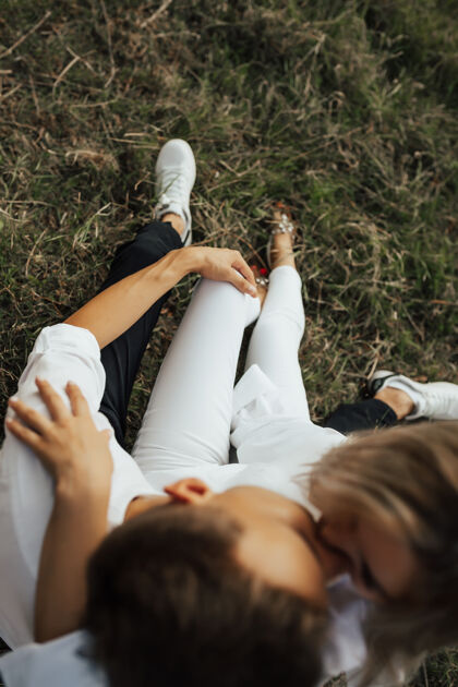生活方式一对年轻夫妇坐在夏日公园的绿草上 拥抱着接吻选择性集中注意力 集中在手上可爱拥抱风景