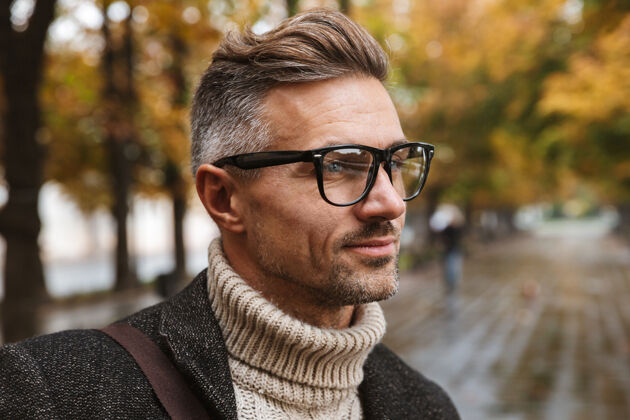 户外图为30多岁的留胡子男子戴着眼镜 在户外穿过秋季公园肌肉发达享受夹克