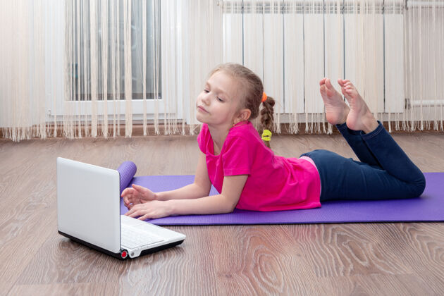 健康女孩看了笔记本电脑在线课程 做健身操锻炼房子女孩