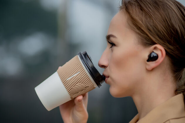经理高加索女人拿着智能手机站在街道建筑的背景下咖啡无线技术时尚