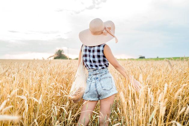 旅程女孩戴着帽子在田里背着玉米穗 夏天收获了庄稼面包自由概念休息葡萄酒阳光