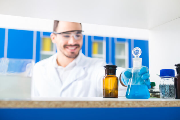 生物学实验室在里面男性手拿实验眼镜的选择性聚焦 将液体倒进并站在表面化学临床设施
