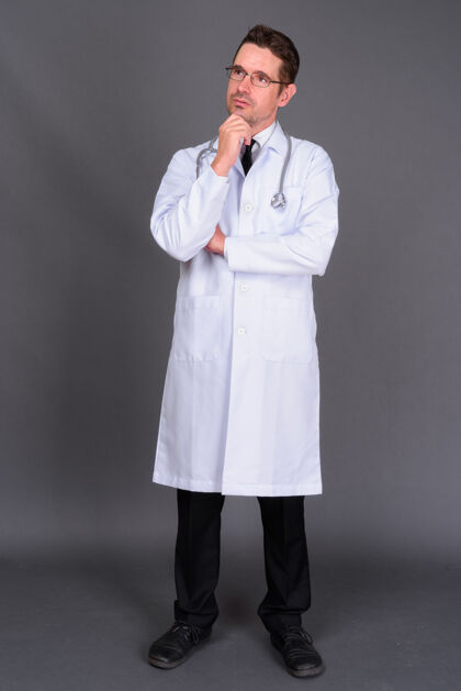 男人长着胡子的帅哥医生戴着眼镜靠着灰墙吸引力胡茬医生