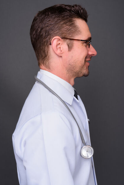 视图长着胡子的帅哥医生戴着眼镜靠着灰墙头部吸引力实验室
