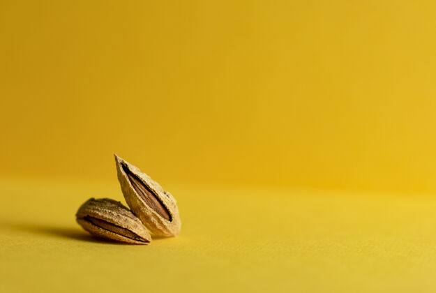 坚果黄色背景上有两颗没有去皮的杏仁植物杏仁配料