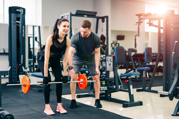 健身房教练练习锻炼“蹲”和“死亡电梯”使用杠铃与女客户运动健康举重