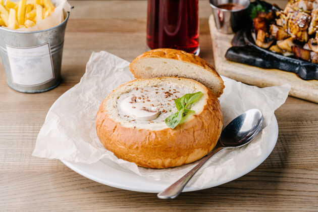 菜肴自制蘑菇汤放在咖啡馆桌子上的面包碗里服务蘑菇膳食