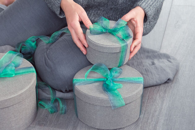 坐女人用灰色的圆盒子和绿色的丝带包装礼物女士女士绿丝带