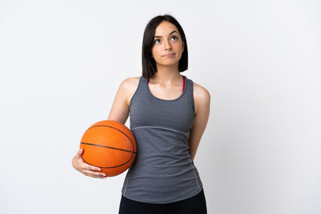 运动装打篮球的年轻女子孤零零地站在白色的地面上仰望球身体篮球