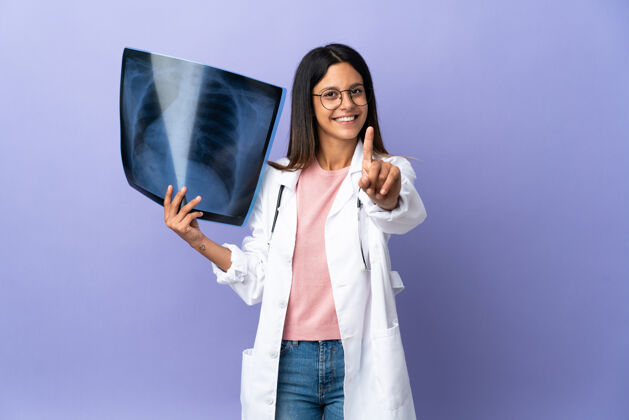手年轻的女医生拿着一张X光片 举起一根手指专业手势医学