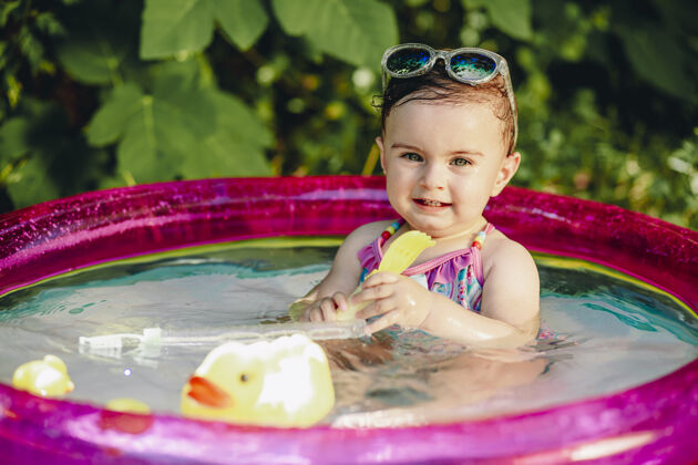 婴儿十个月大的宝宝在游泳池里用黄色的橡皮鸭玩具享受夏天的温暖女儿欢乐美丽