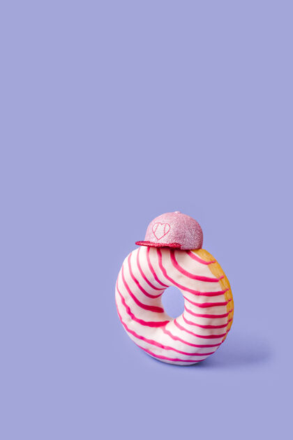 视图一个粉红色和白色釉面的甜甜圈站在一个波普艺术风格的粉红色帽子帽子五颜六色小吃