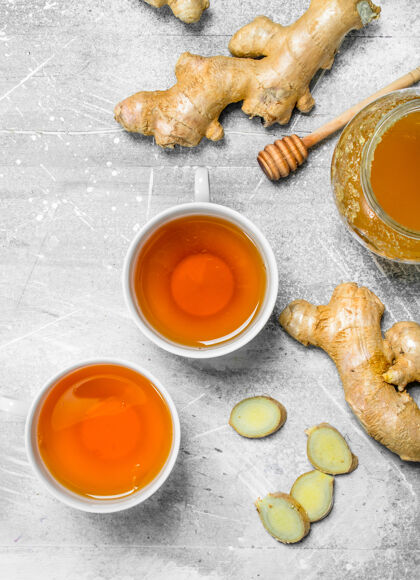 粗糙姜茶和蜂蜜放在白色的木桌上护理植物维生素