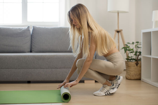 女孩家锻炼女人在家锻炼后滚动瑜伽垫设备地板壁板
