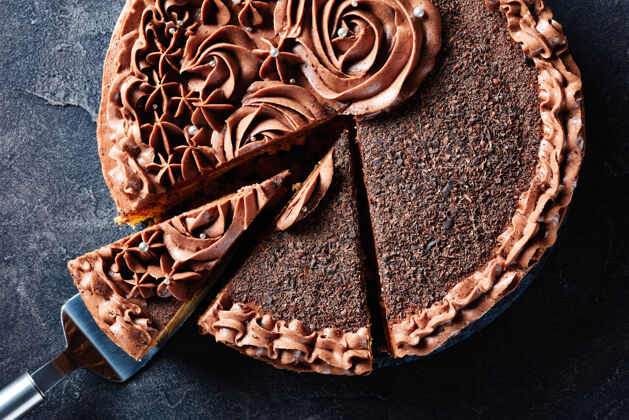 混凝土特写镜头的巧克力蛋白酥皮节日蛋糕顶部巧克力奶油玫瑰和银色可食用德拉吉切成片在一个盘子上的混凝土桌上 从上面的水平视图蛋糕抹刀食物玫瑰