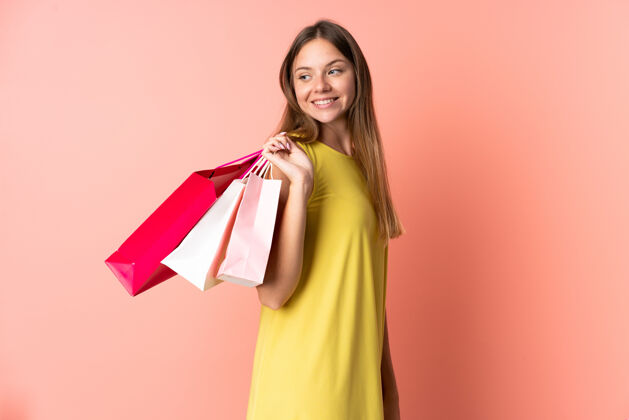年轻一位年轻的立陶宛妇女 手拿购物袋 独自站在粉色的背景下 回首往事销售成人女性