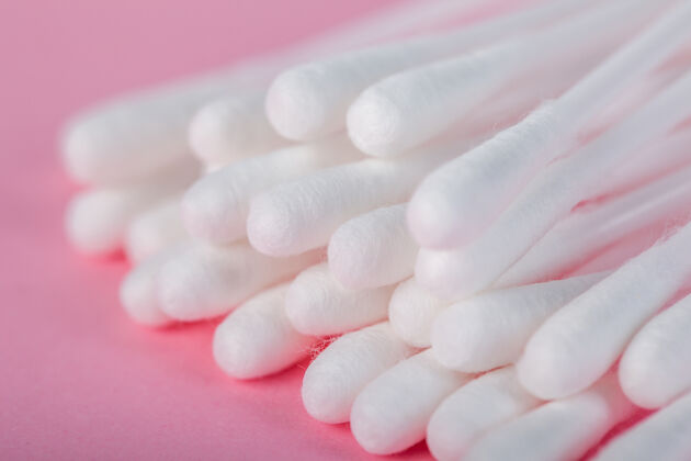 棉花在粉红色的地板上擦耳朵用的棍子拭子化妆品棒