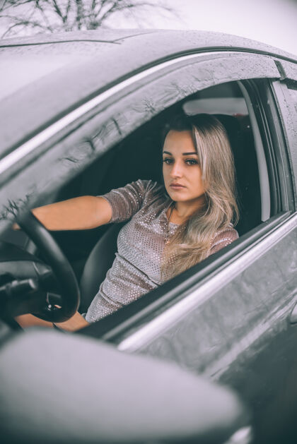 年轻美丽的年轻女商人在冬天开着灰色的车车窗时尚商务女性