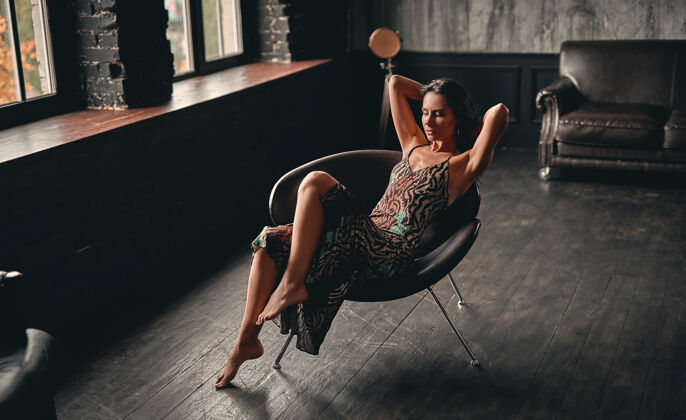 坐着一个漂亮的黑发女人的肖像 穿着裙子 坐在扶手椅上摆姿势 展现出美丽的修长双腿深色女士成人