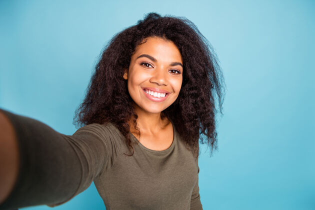毛衣积极开朗的非裔美国女孩的特写照片在假日感到乐趣自由时间周末让自拍穿休闲风格的套头衫隔离蓝色墙壁黑发拍摄女人