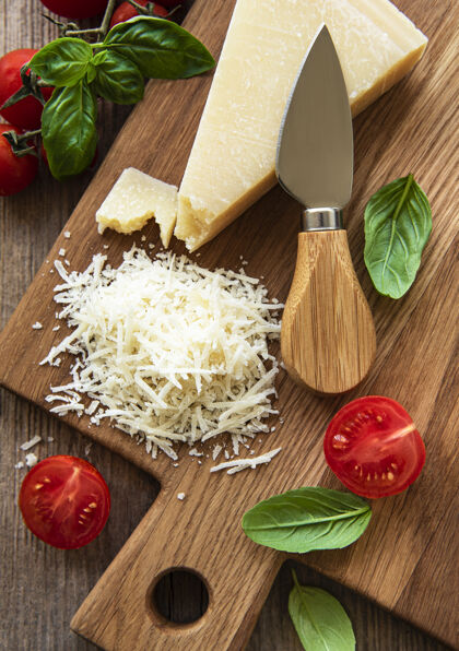帕尔马干酪切碎的帕玛干酪 罗勒和西红柿放在砧板上新鲜意大利美食