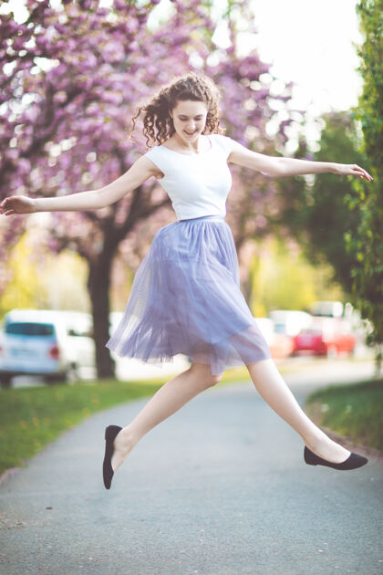 散步年轻女孩在樱花树下跳啊跳啊跳树女孩舞蹈