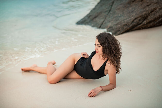 放松优雅的女人 留着长长的头发 穿着黑色豪华比基尼 在沙滩上放松海滩夏天假期泰国热带海滩