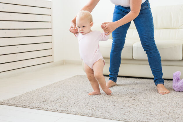 帮助婴儿学走路的第一步在白色阳光下生活房间.鞋类为了孩子妈妈儿子孩子