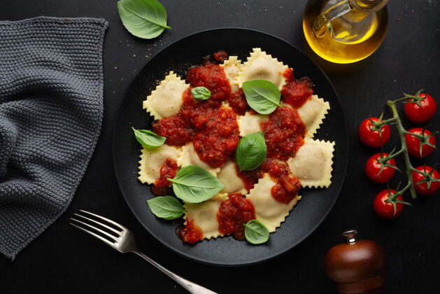 健康美味的意大利馄饨配番茄酱和罗勒 放在深色盘子里草药膳食食物