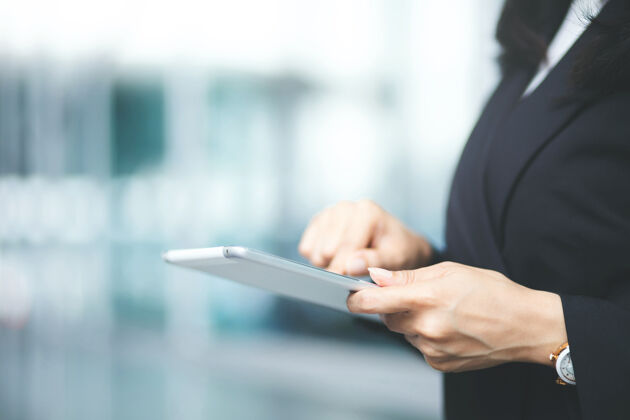 商务女性女商人正在用数字平板电脑轻表使用手机特写