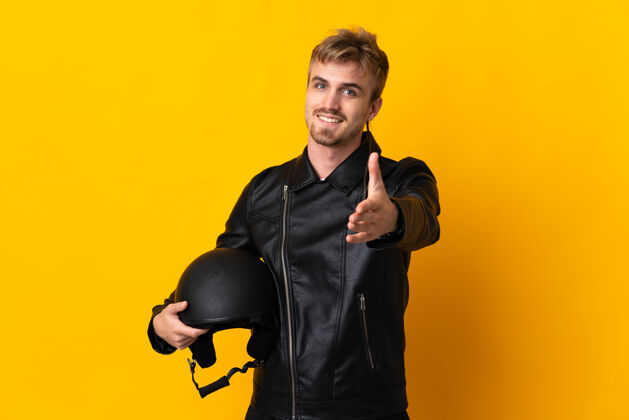 司机一个戴着摩托车头盔的男人孤零零地站在黄色的地板上 握手示意成交人年轻人摩托车手