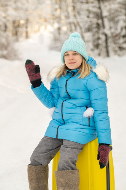 女人冬天 一个穿着毡靴的女孩在一个寒冷的雪天坐在手提箱上车站行李冒险