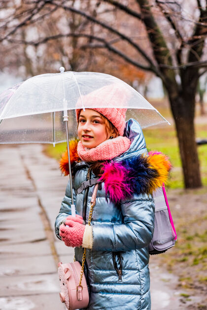 肖像金发碧眼的女孩穿着夹克带着透明的雨伞在外面的雨中御寒雨天气寒冷
