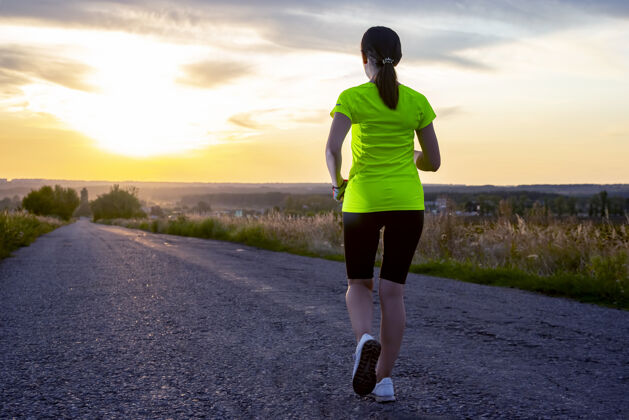 跑步女运动员顶着夕阳在路上跑了一段距离事件人运动鞋