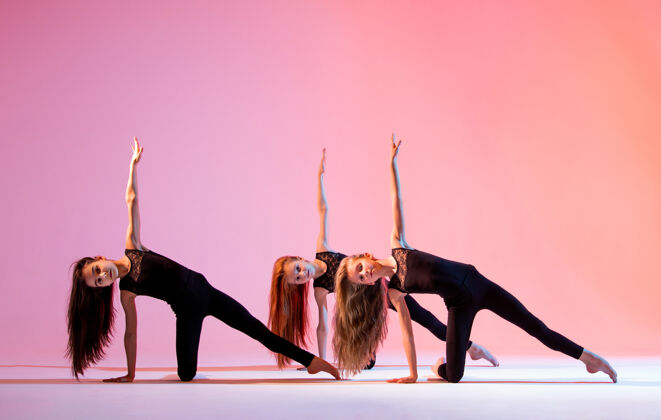活跃一组三个芭蕾舞女孩 一头飘逸的长发 穿着黑色紧身套装 在红色背景上跳舞表情芭蕾舞团体
