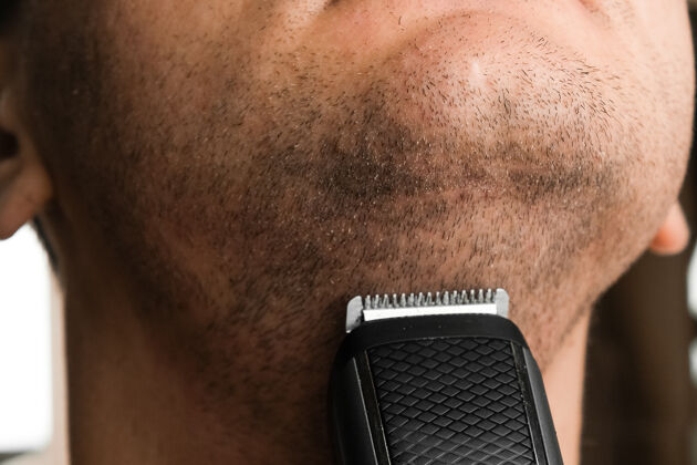面部剃短发的男人残茬后电动剃须刀剃须概念烦躁剪剃须刀