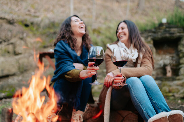 野餐年轻快乐的女人笑着 捧着一杯红葡萄酒葡萄酒女性温暖的天气篝火户外活动概念喝酒情侣玻璃杯