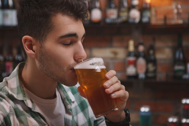 品尝一个年轻人在酒吧喝着美味的啤酒的特写镜头工艺庆典男人