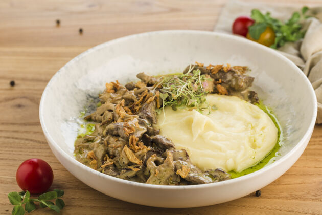 烹饪把土豆泥放在一个盘子里 放在一个浅色的木头表面上砂锅盘子牛肉