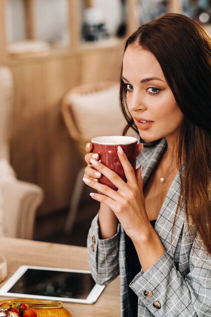 休闲一个女孩在咖啡店喝咖啡 一个漂亮的女孩的头发脸饮料早晨