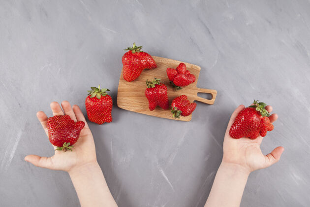 水果孩子们的手拿着形状有趣的有机物草莓.木制用鲜亮难看的浆果做成的盘子美味异国情调甜